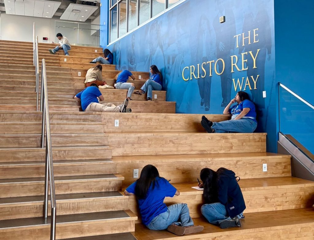 Students studying on the steps beneath the Cristo Rey Way mural
